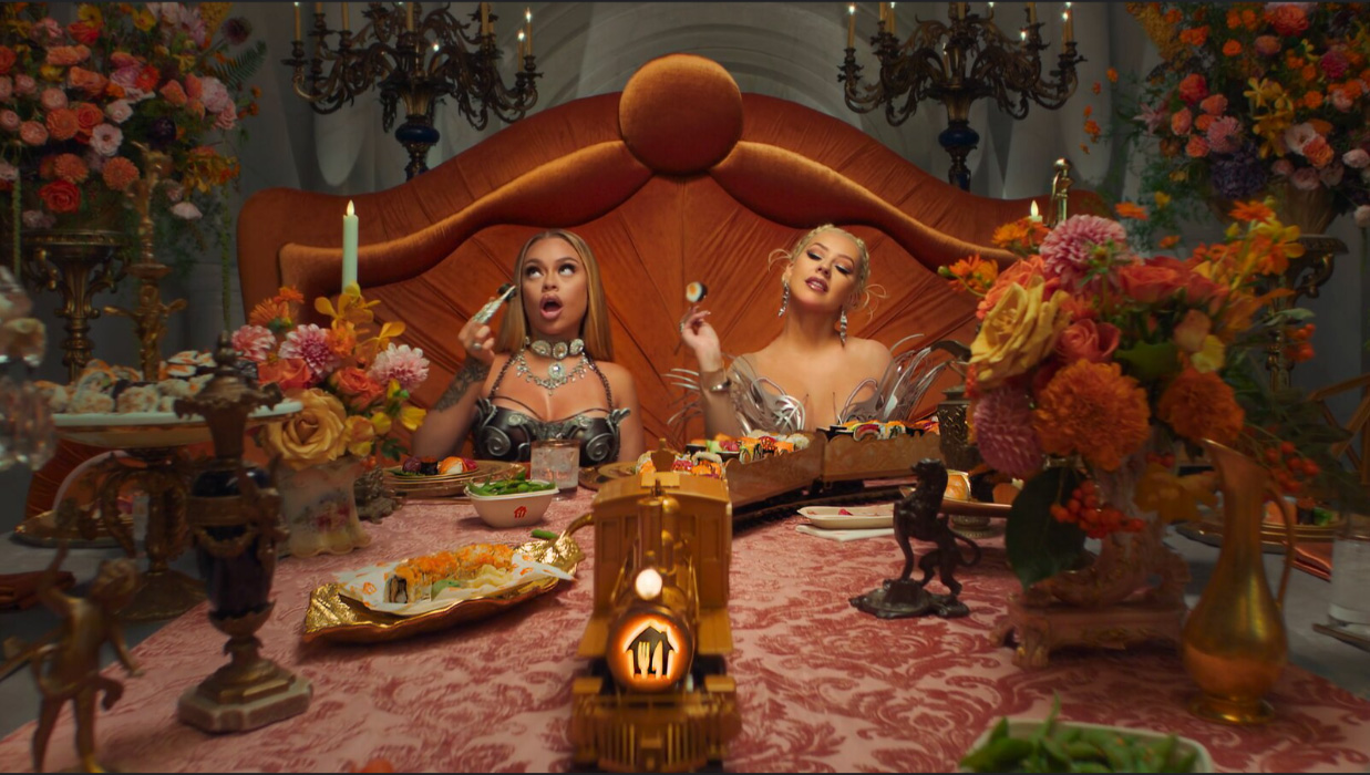 Christina Aguilera and Latto sat at an opulent dining table.