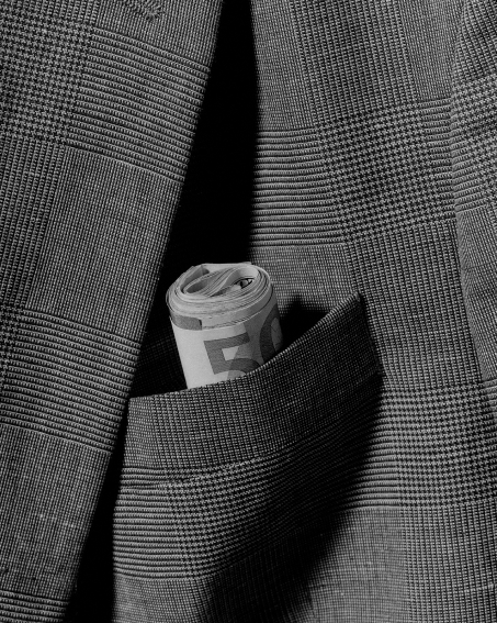 A black and white image of a suit pocket with a roll of money